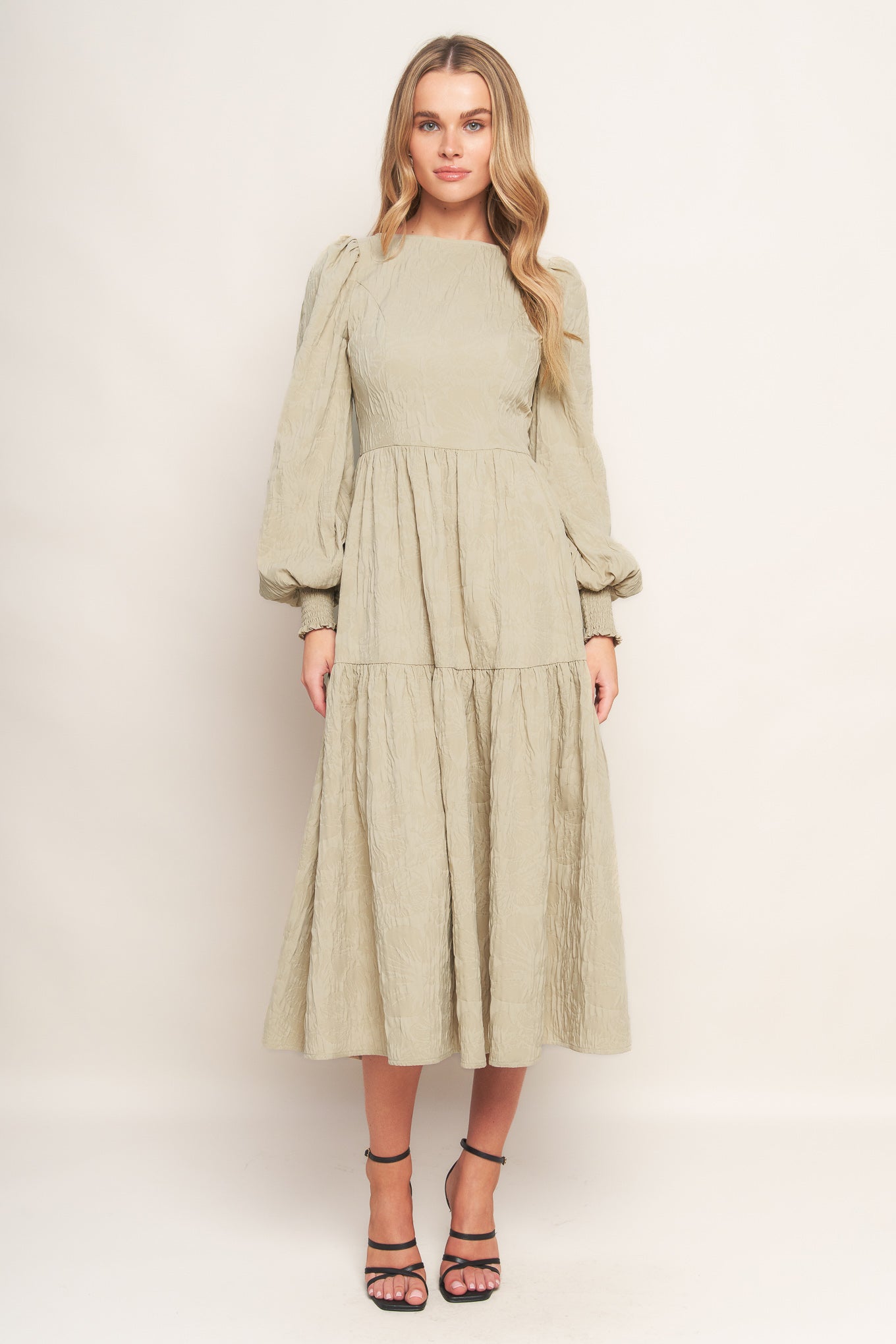 A textured woven midi dress featuring wide neckline, long sleeve with smocked cuff, tiered skirt and back zipper closure