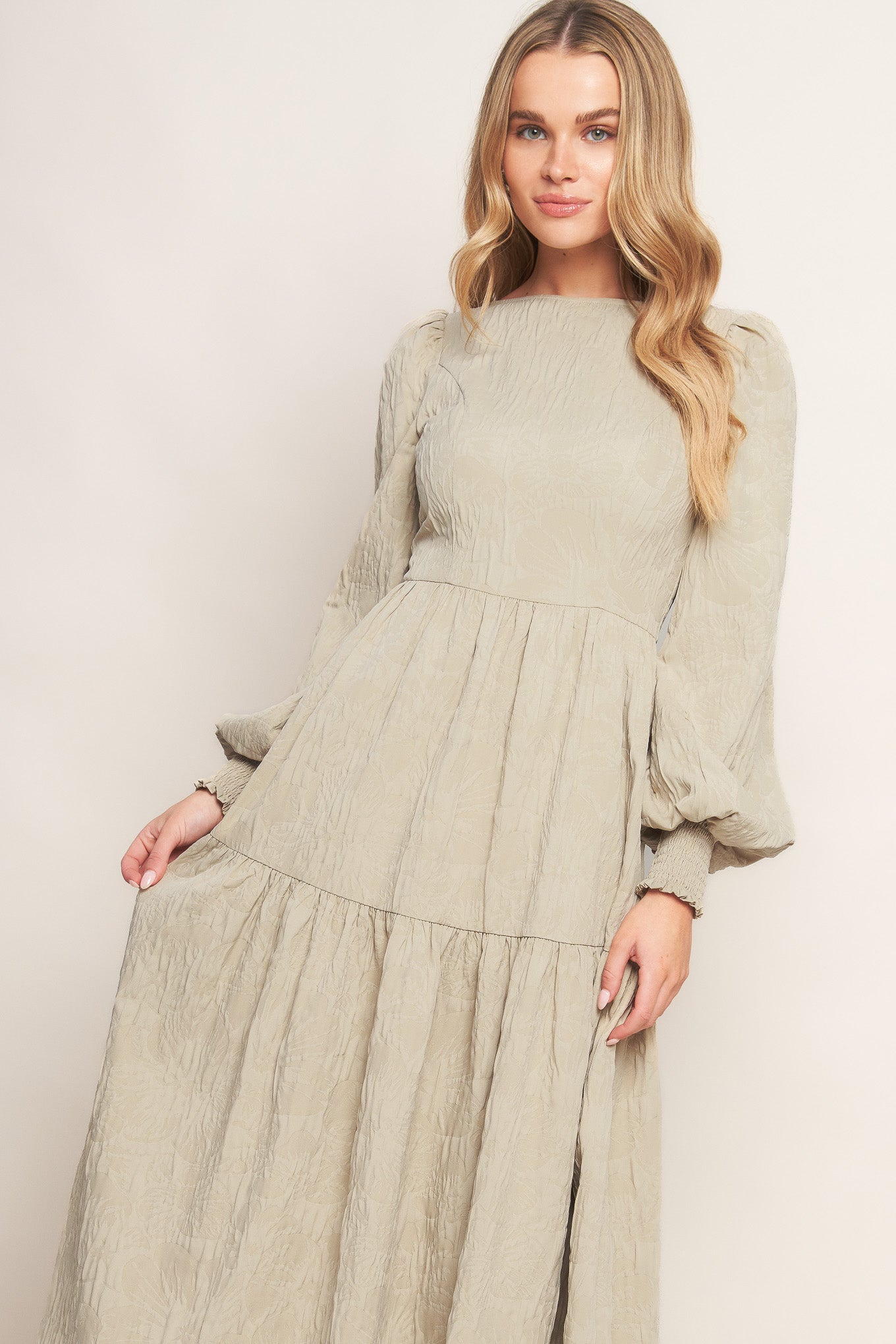 A textured woven midi dress featuring wide neckline, long sleeve with smocked cuff, tiered skirt and back zipper closure