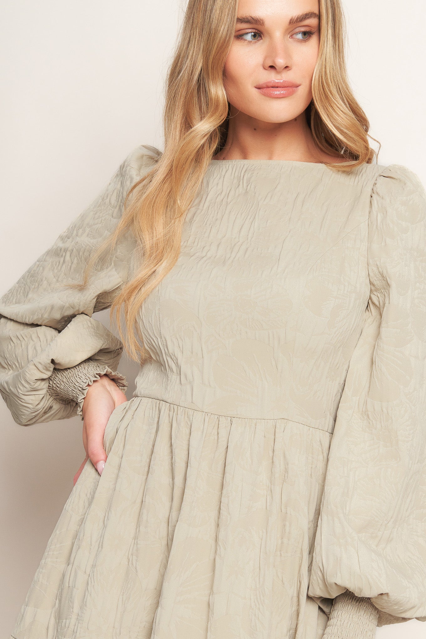 A textured woven midi dress featuring wide neckline, long sleeve with smocked cuff, tiered skirt and back zipper closure