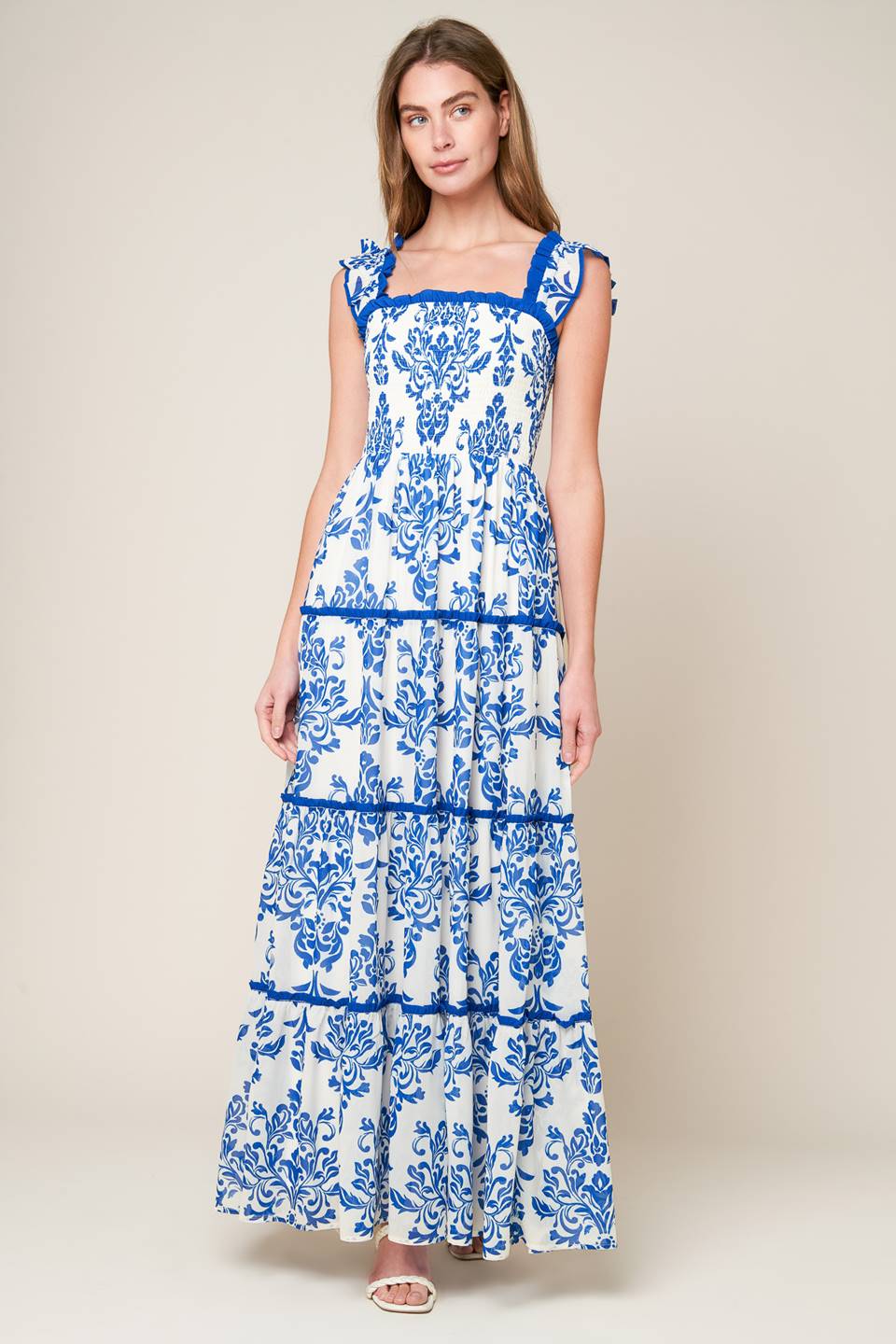 woven maxi dress boasts a printed design with a square neckline, ruffled sleeves, smocked bodice, and tiered skirt, creating a stylish, feminine look.