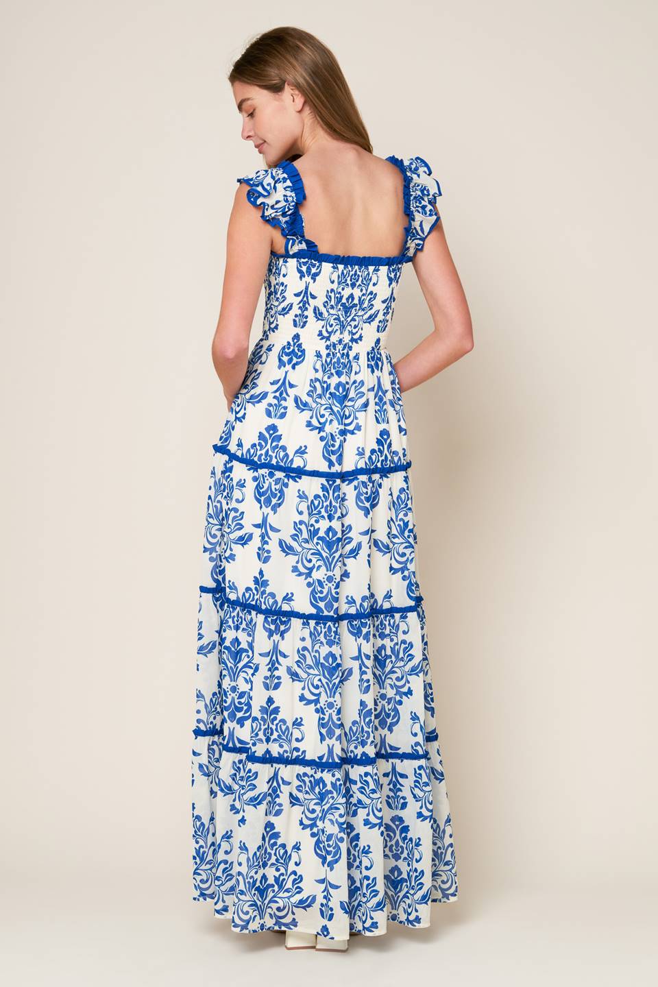 woven maxi dress boasts a printed design with a square neckline, ruffled sleeves, smocked bodice, and tiered skirt, creating a stylish, feminine look.