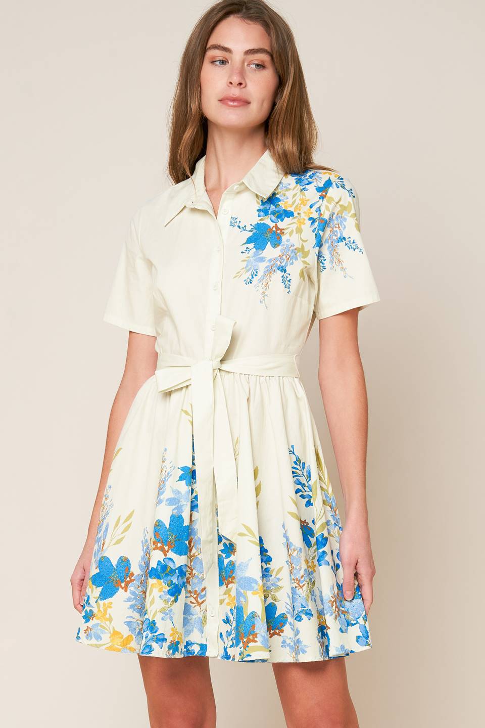 A printed woven mini dress featuring shirt collar, button down, short sleeve, self sash tie and full skirt.