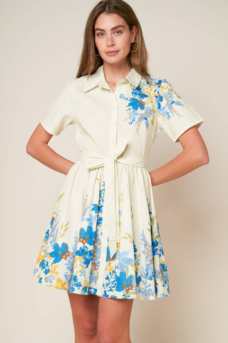 A printed woven mini dress featuring shirt collar, button down, short sleeve, self sash tie and full skirt.