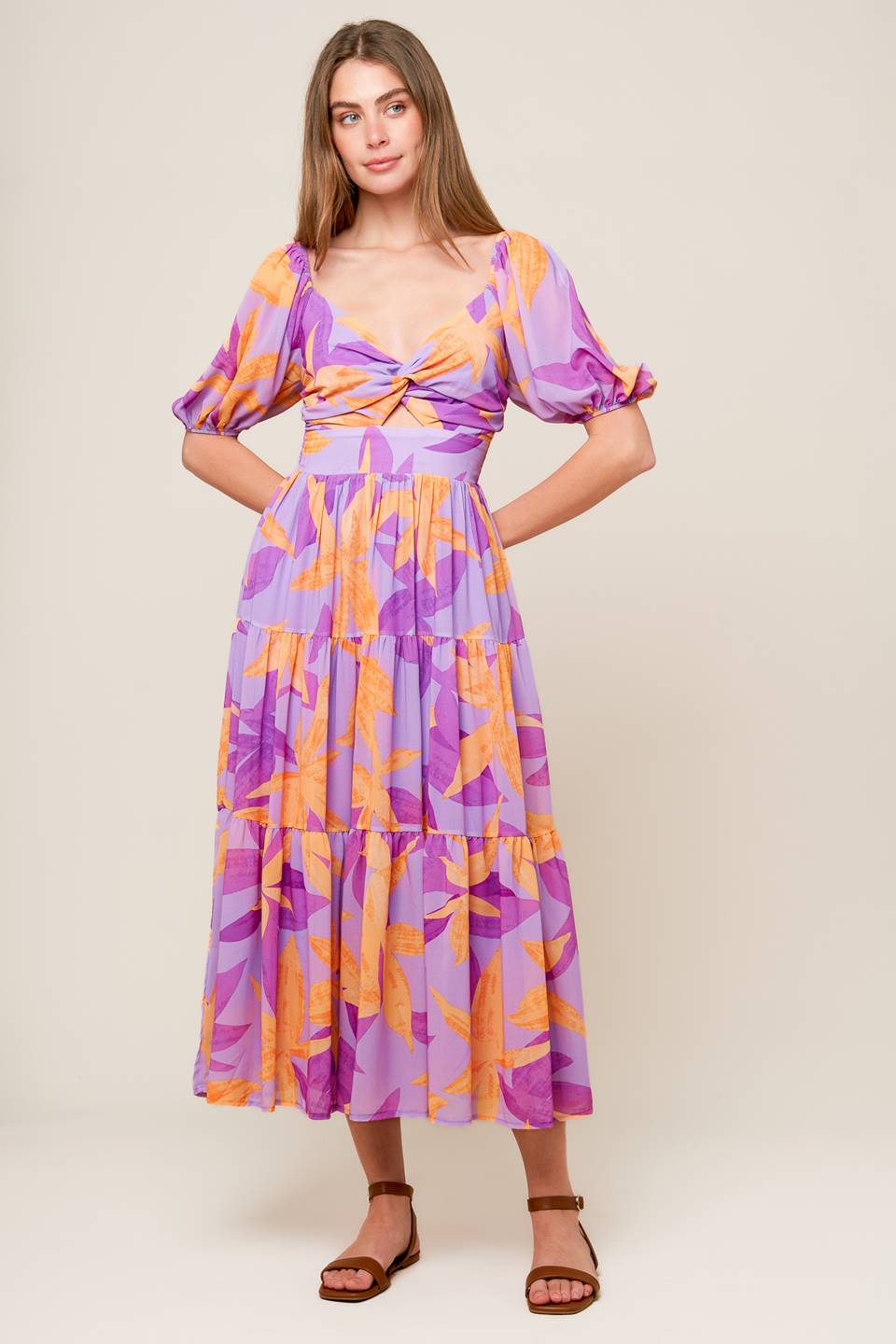 A printed woven midi dress featuring sweetheart neckline with front twist bodice, short sleeve, center front cut out, tiered skirt and smocked back bodice.