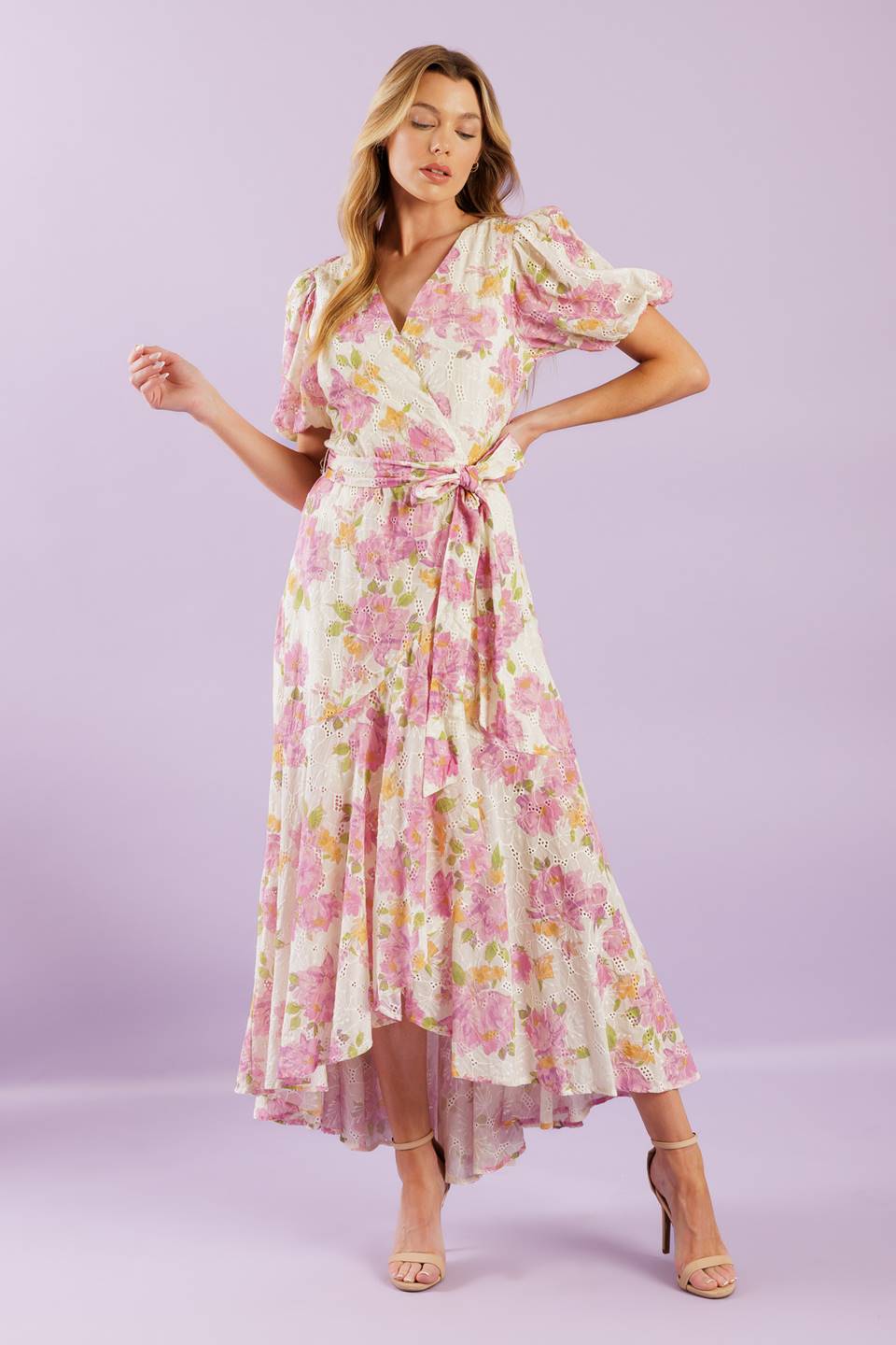 A printed woven lace midi dress featuring surplice neckline, short puff sleeve, self sash, faux wrap with hi-lo and ruffled hemline