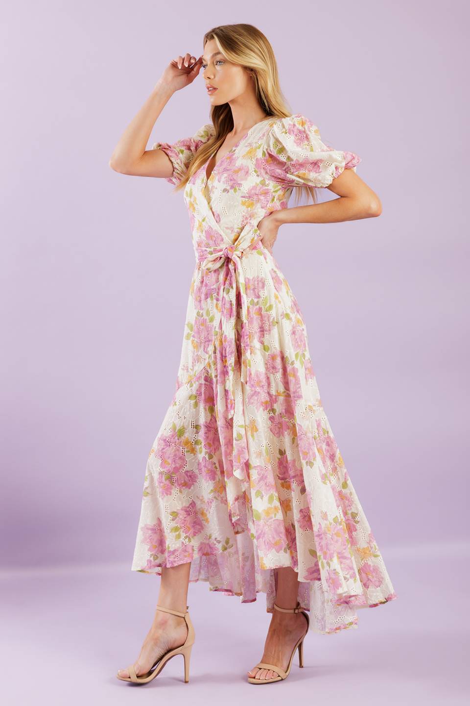 A printed woven lace midi dress featuring surplice neckline, short puff sleeve, self sash, faux wrap with hi-lo and ruffled hemline