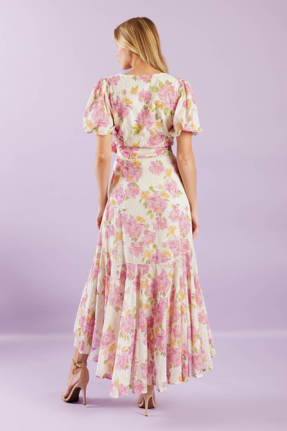 A printed woven lace midi dress featuring surplice neckline, short puff sleeve, self sash, faux wrap with hi-lo and ruffled hemline