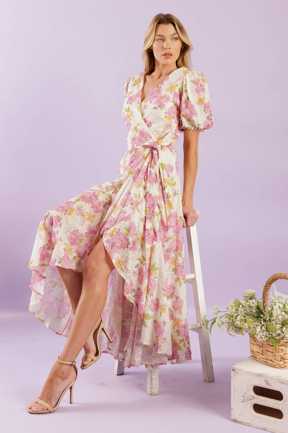 A printed woven lace midi dress featuring surplice neckline, short puff sleeve, self sash, faux wrap with hi-lo and ruffled hemline