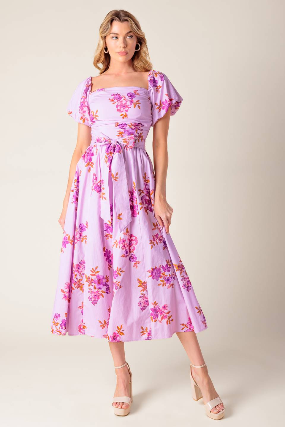 A lavender printed woven midi dress featuring on/off shoulder neckline, shirred bodice, self sash tie, full skirt and smocked back bodice.