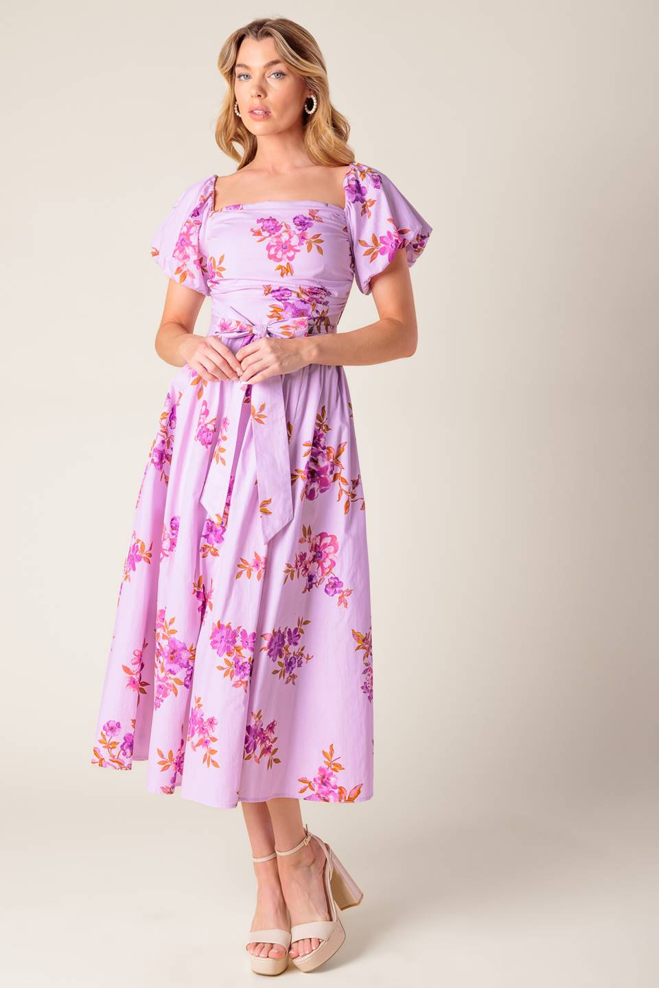 A lavender printed woven midi dress featuring on/off shoulder neckline, shirred bodice, self sash tie, full skirt and smocked back bodice.