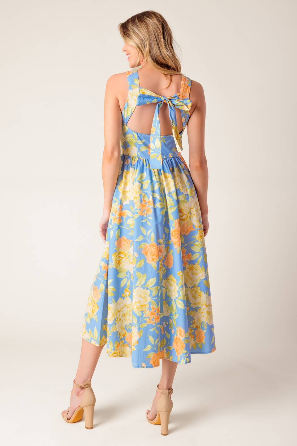 A powder blue floral printed woven midi dress featuring round neckline, sleeveless, full skirt, open back with tie and zipper closure.