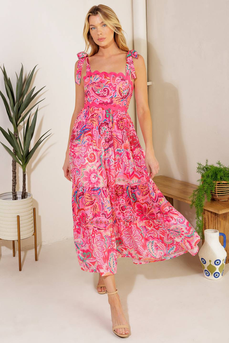 
A printed woven midi dress featuring straight neckline, shoulder ties, ric rac ribbon trim, tiered skirt and smocked back bodic