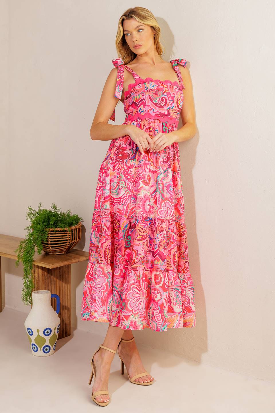 
A printed woven midi dress featuring straight neckline, shoulder ties, ric rac ribbon trim, tiered skirt and smocked back bodic