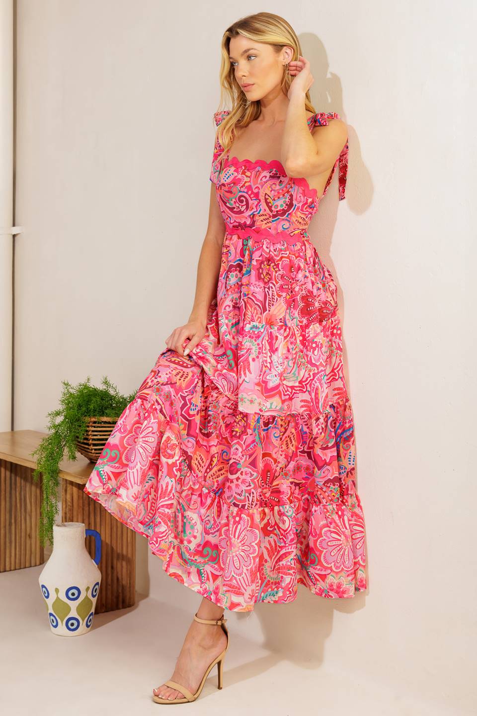 
A printed woven midi dress featuring straight neckline, shoulder ties, ric rac ribbon trim, tiered skirt and smocked back bodic