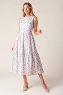 A printed woven eyelet midi dress featuring round neckline, sleeveless, ruffled hem, U back with tie and zipper closure