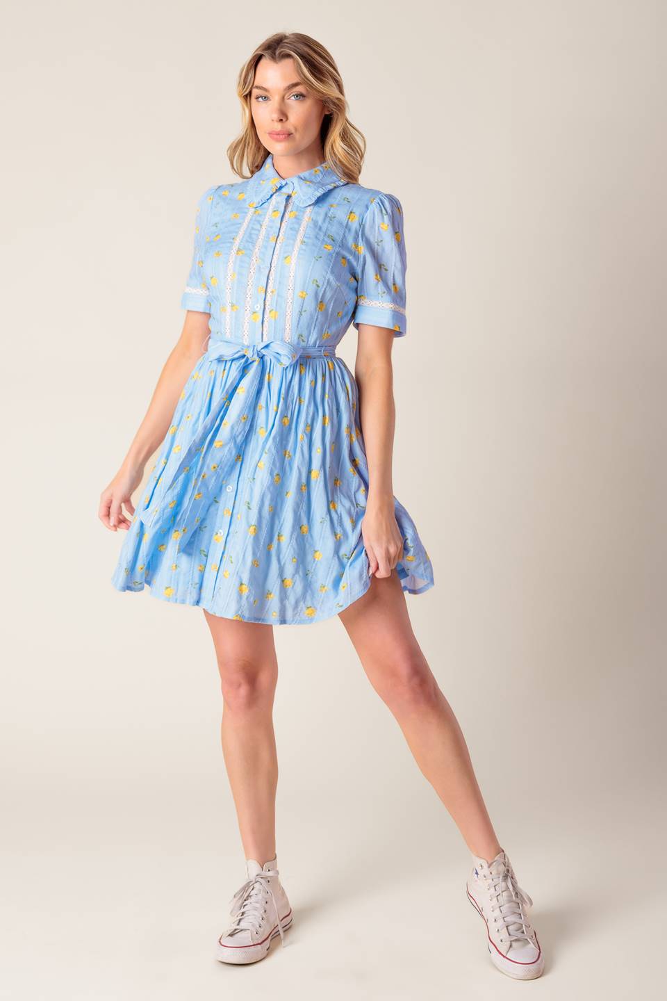 A blue printed woven mini dress featuring collar, button down, short sleeve, lace inset, self sash and full skirt.