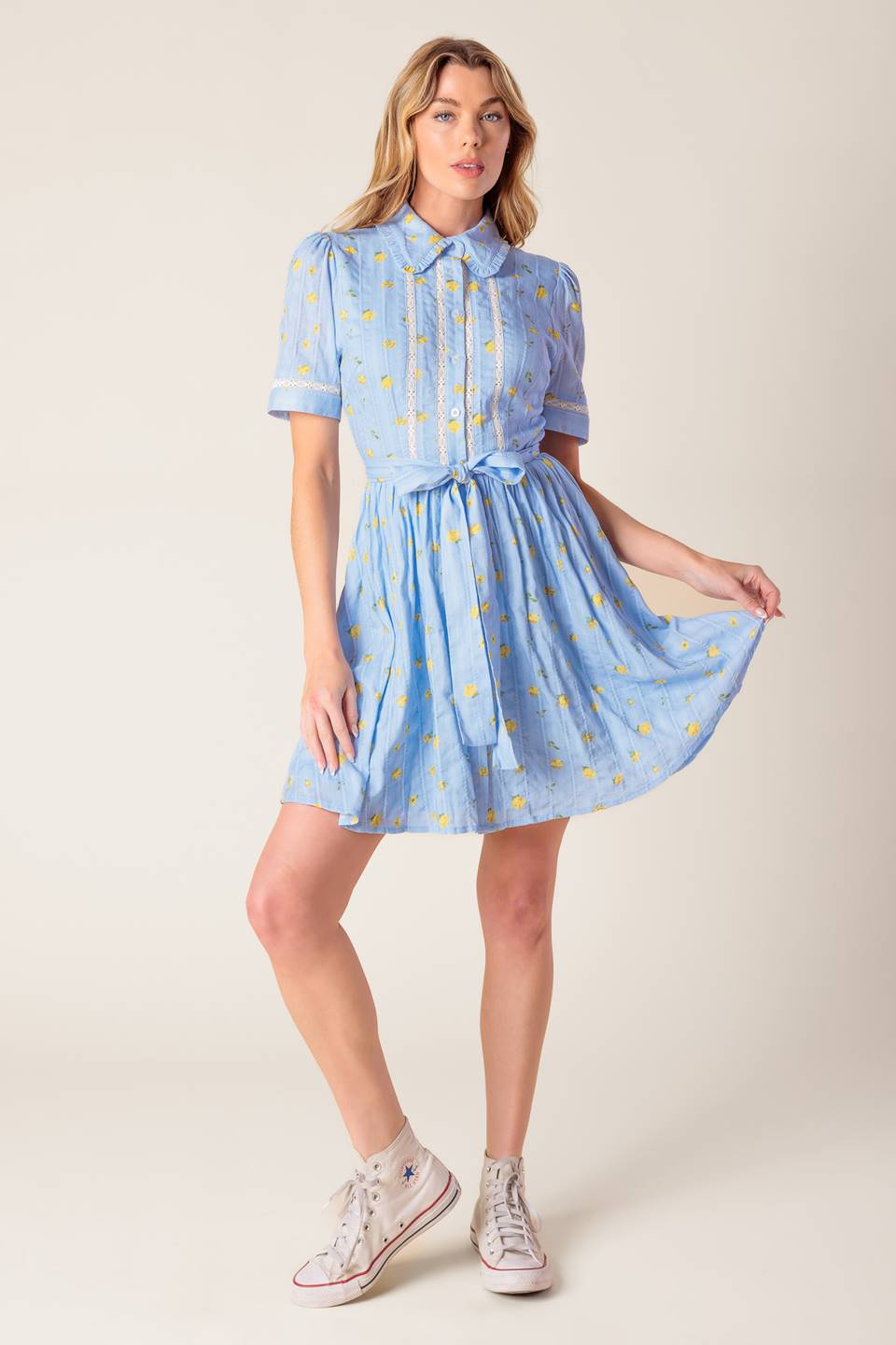 A blue printed woven mini dress featuring collar, button down, short sleeve, lace inset, self sash and full skirt.