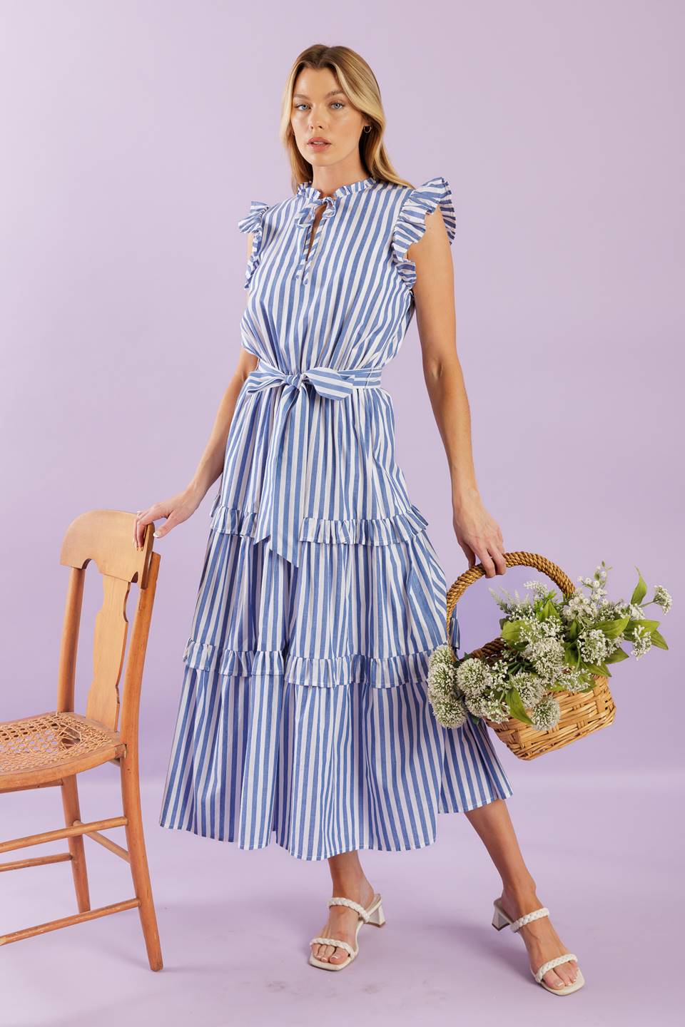 A striped woven midi dress featuring ruffled neckline with front tie, short ruffled sleeve, elasticized waist, self sash tie and tiered skirt with ruffles