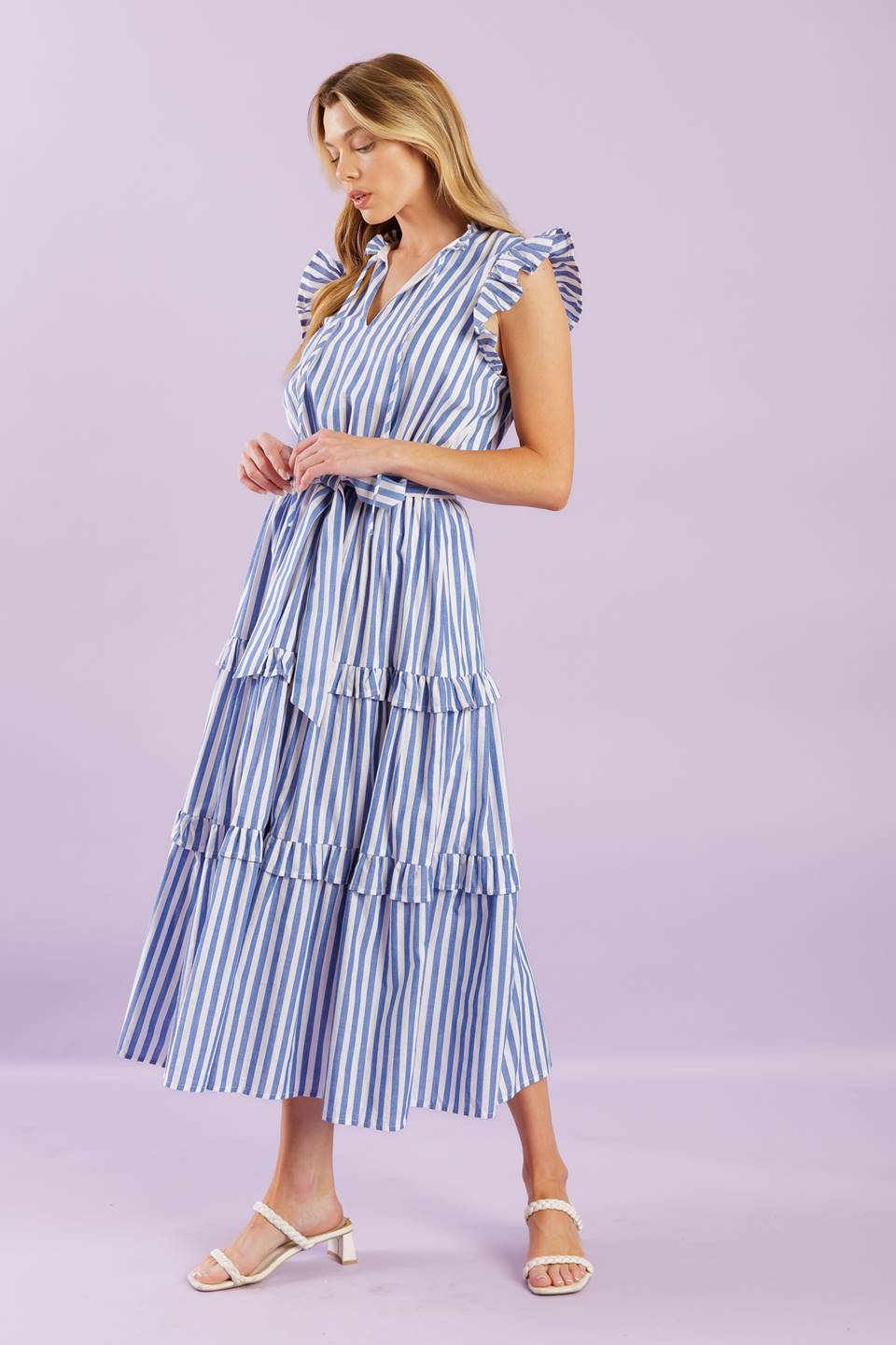 A striped woven midi dress featuring ruffled neckline with front tie, short ruffled sleeve, elasticized waist, self sash tie and tiered skirt with ruffles