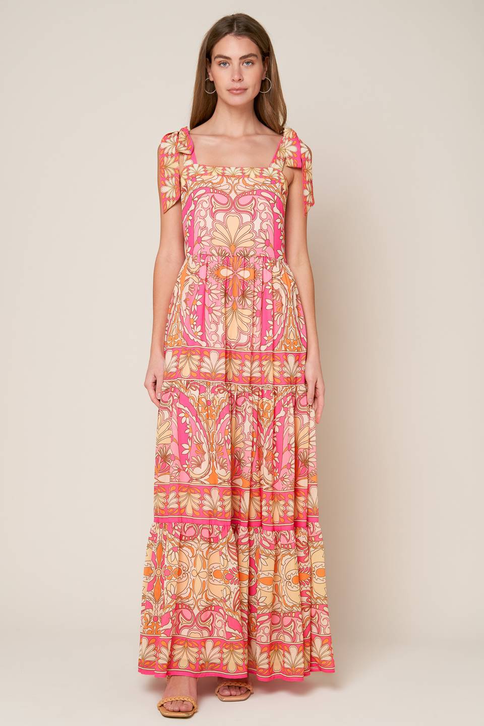 This woven maxi dress showcases a printed design, along with a straight neckline, shoulder tie, tiered skirt, and a back zipper closure.