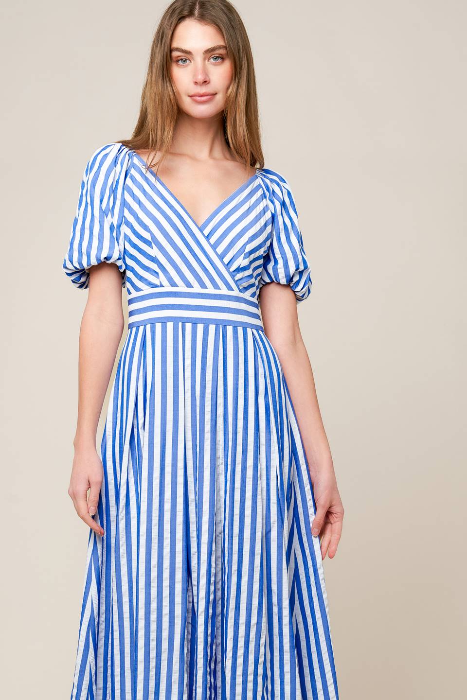 A blue and white striped woven midi dress featuring surplice neckline, short puff sleeve, full skirt and back zipper closure.