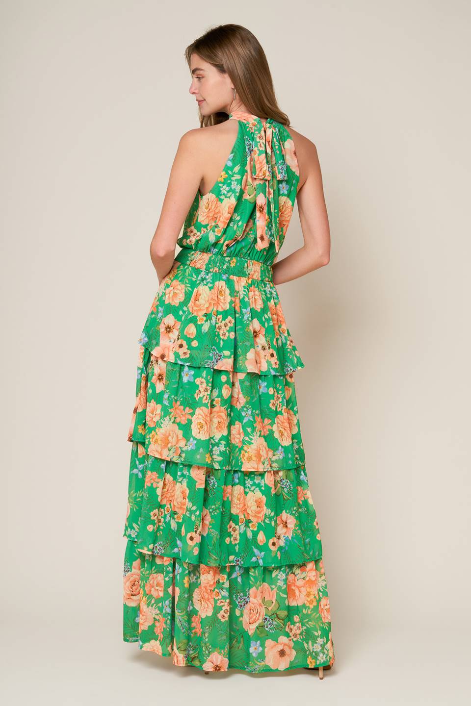 A printed woven maxi dress featuring halter neckline, sleeveless, layered skirt, back neck tie and smocked back waistband