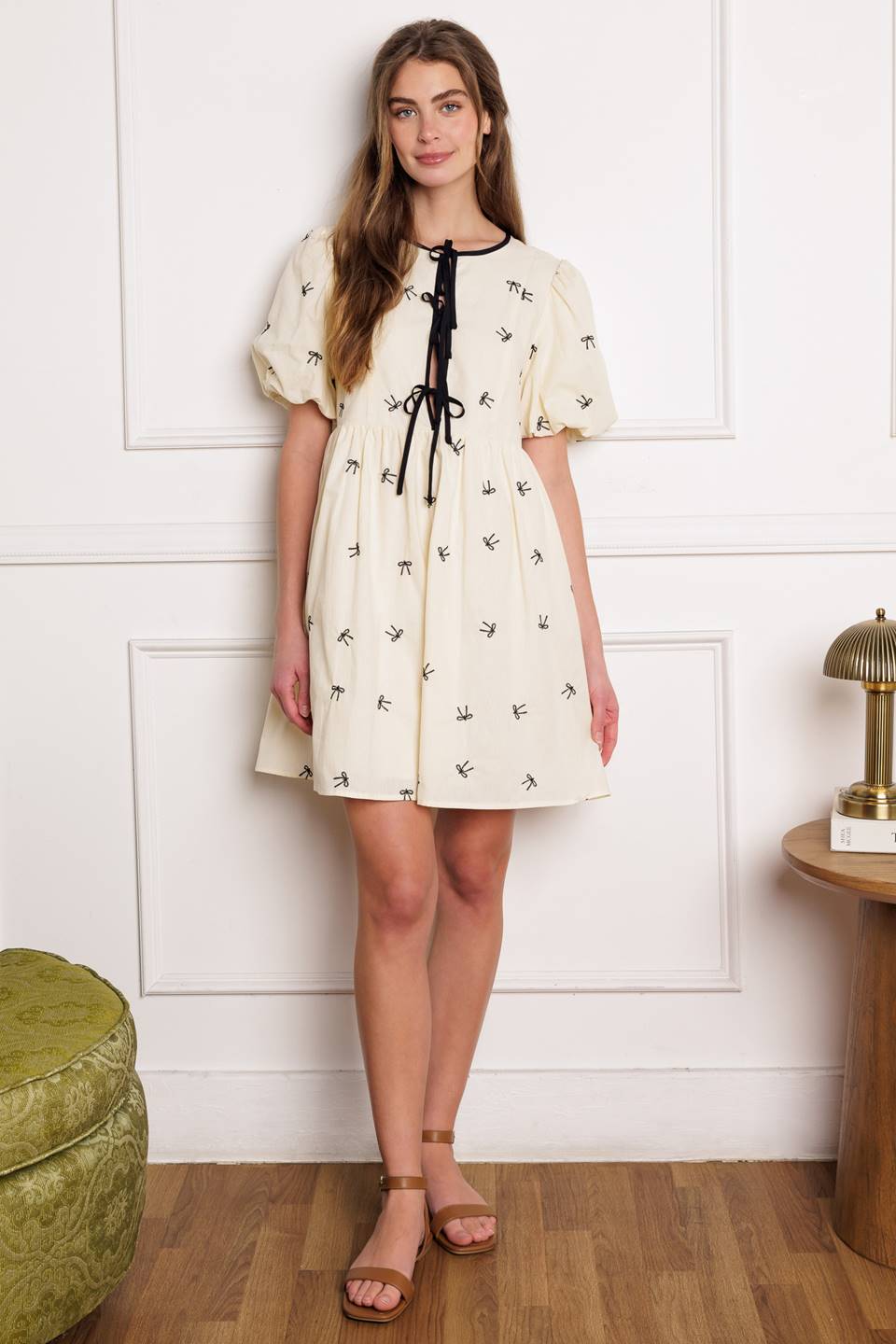 A perfect addition to your wardrobe, this solid embroidered mini dress is designed with a round neckline and adorable front bow ties, accompanied by short puff sleeves.