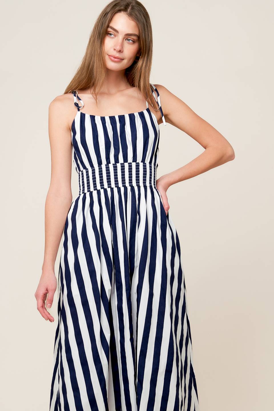 A white and navy striped printed woven midi dress featuring tank bodice with shoulder strap, wide smocked waistband and full skirt.