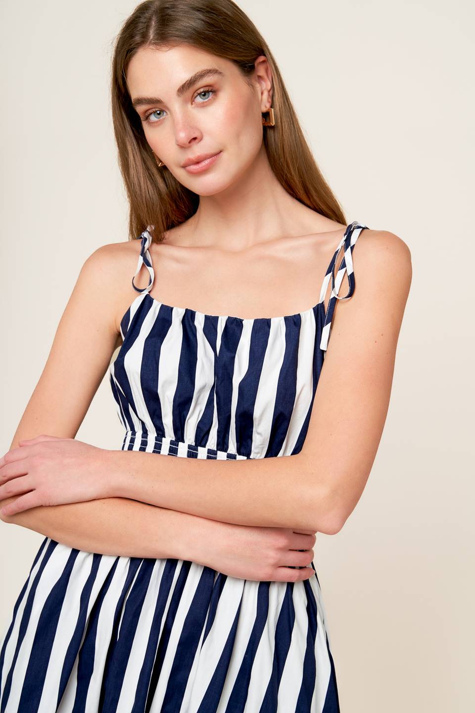 A white and navy striped printed woven midi dress featuring tank bodice with shoulder strap, wide smocked waistband and full skirt.