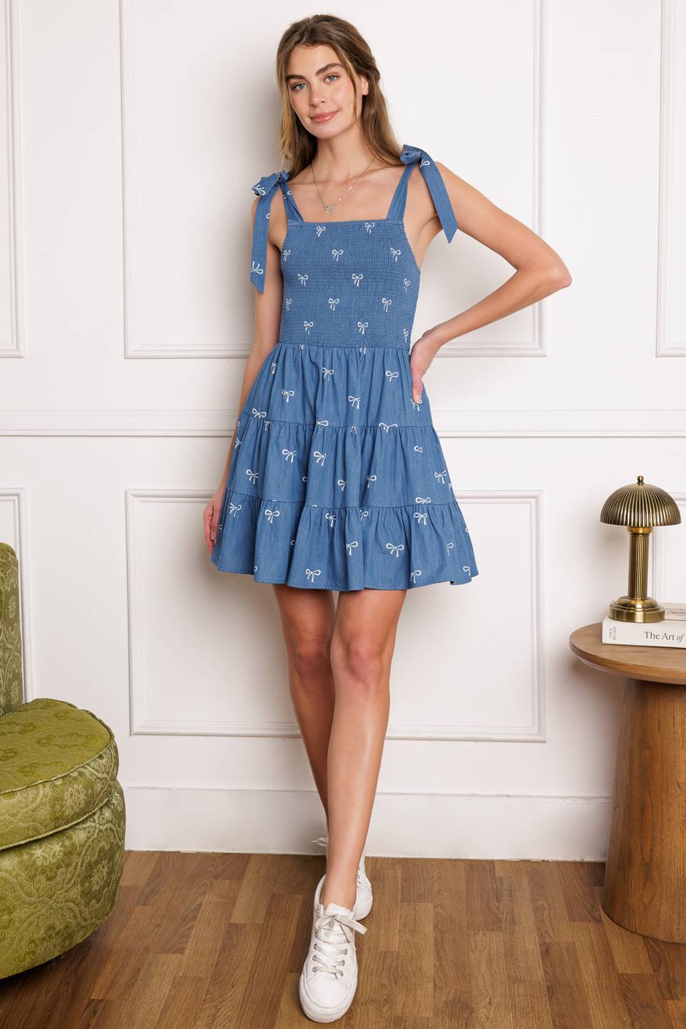 A chic woven mini dress with a solid embroidered design and charming shoulder ties, complete with a smocked bodice and tiered skirt.