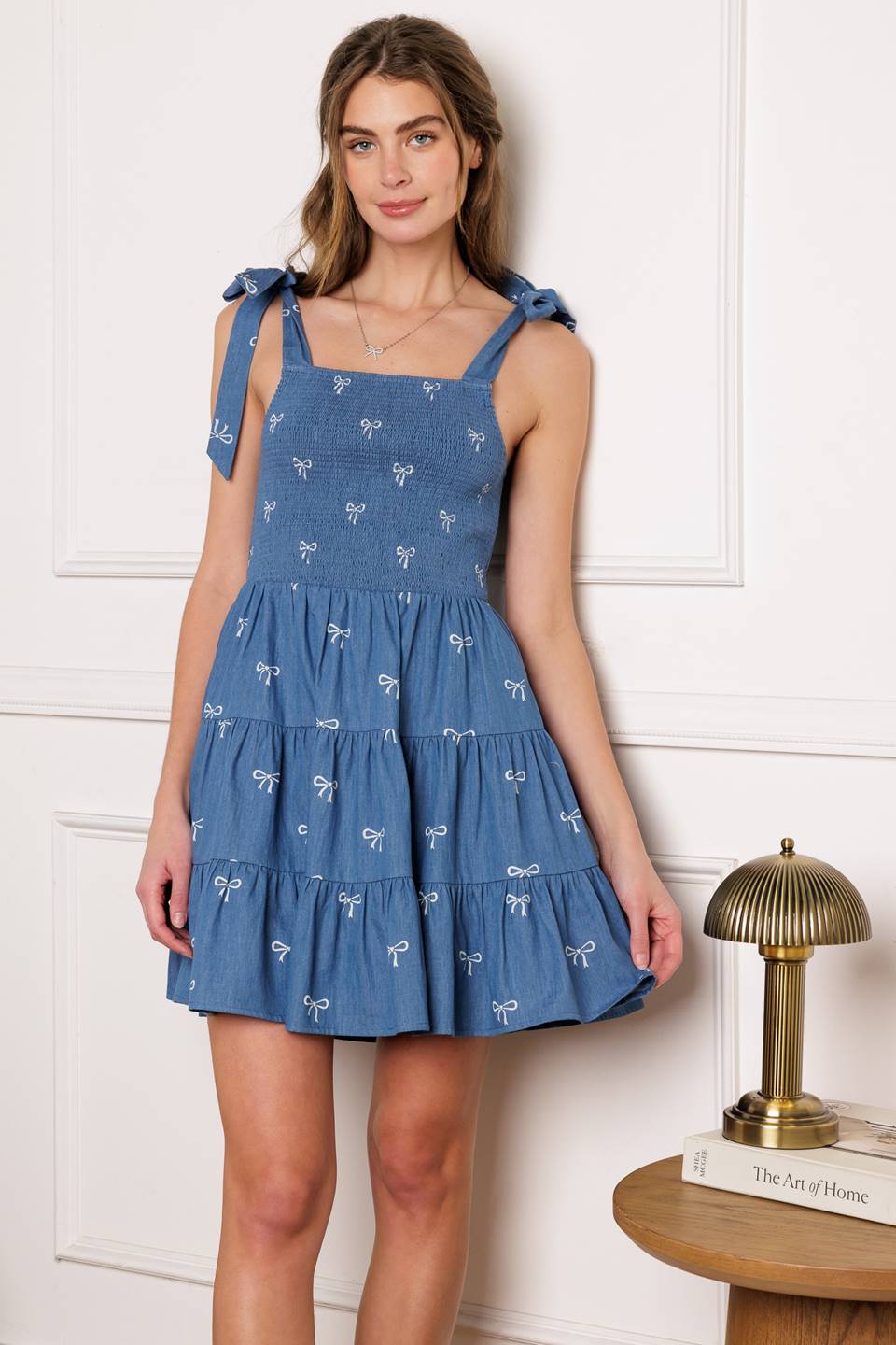 A chic woven mini dress with a solid embroidered design and charming shoulder ties, complete with a smocked bodice and tiered skirt.