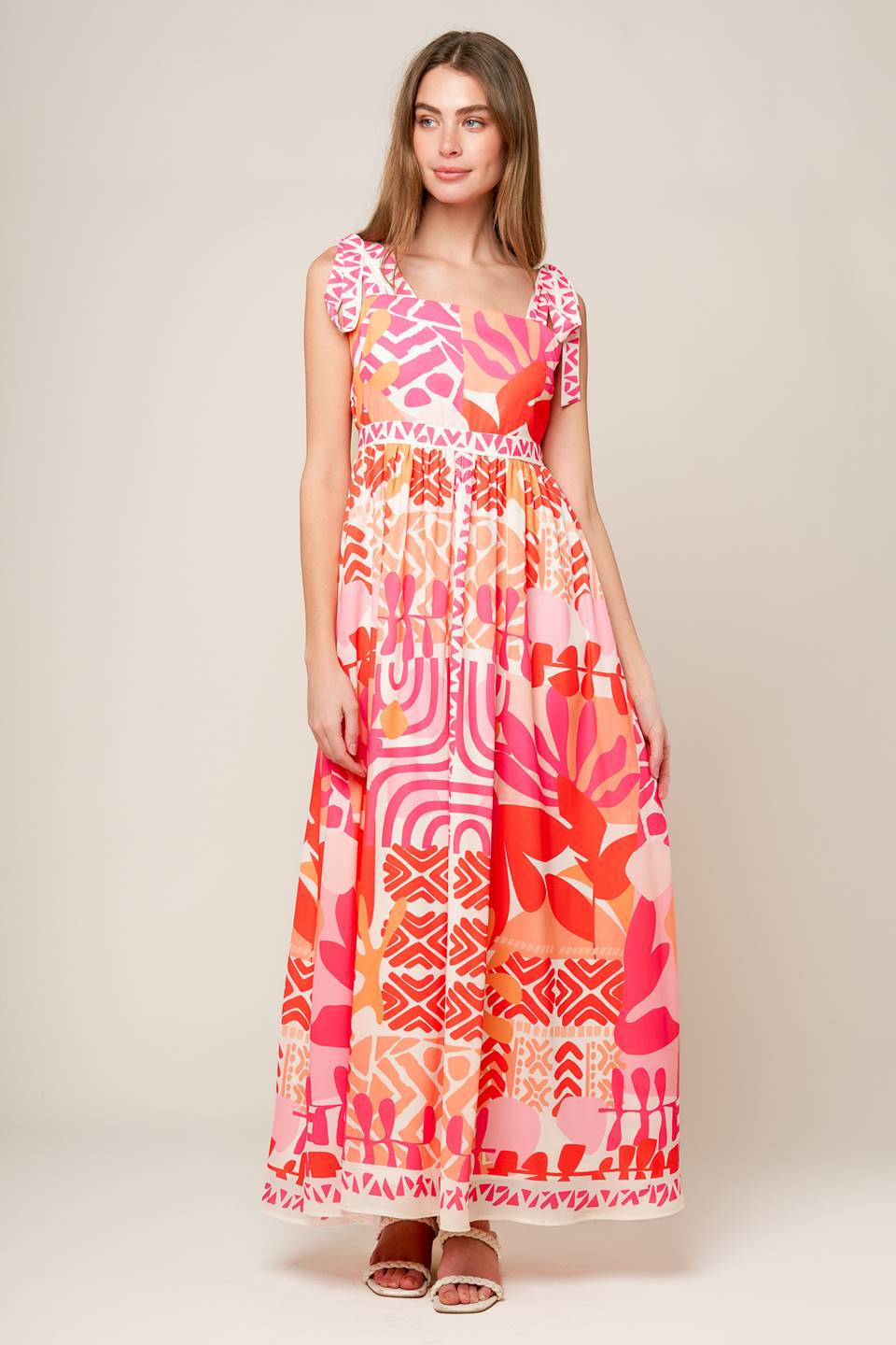 A printed woven maxi dress featuring straight neckline, shoulder tie and back zipper closure.