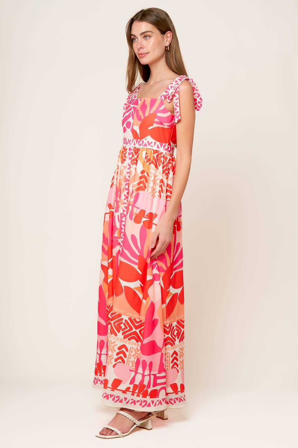 A printed woven maxi dress featuring straight neckline, shoulder tie and back zipper closure.