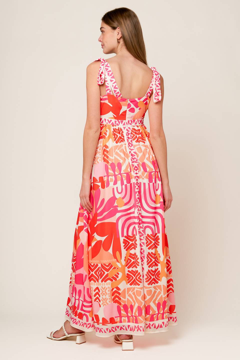 A printed woven maxi dress featuring straight neckline, shoulder tie and back zipper closure.