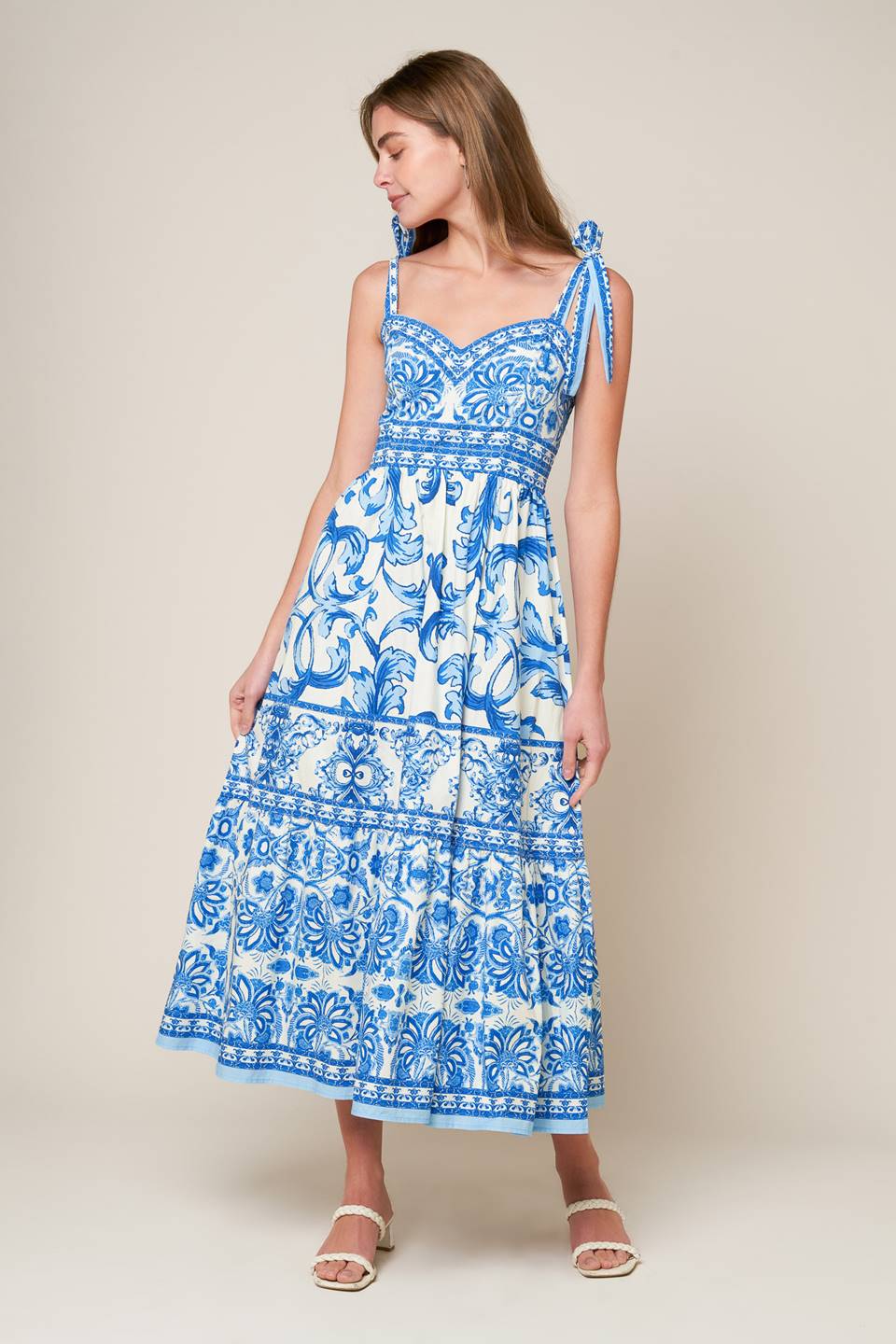 A printed woven midi dress featuring sweetheart neckline, shoulder ties, ruffled hemline and smocked back bodice