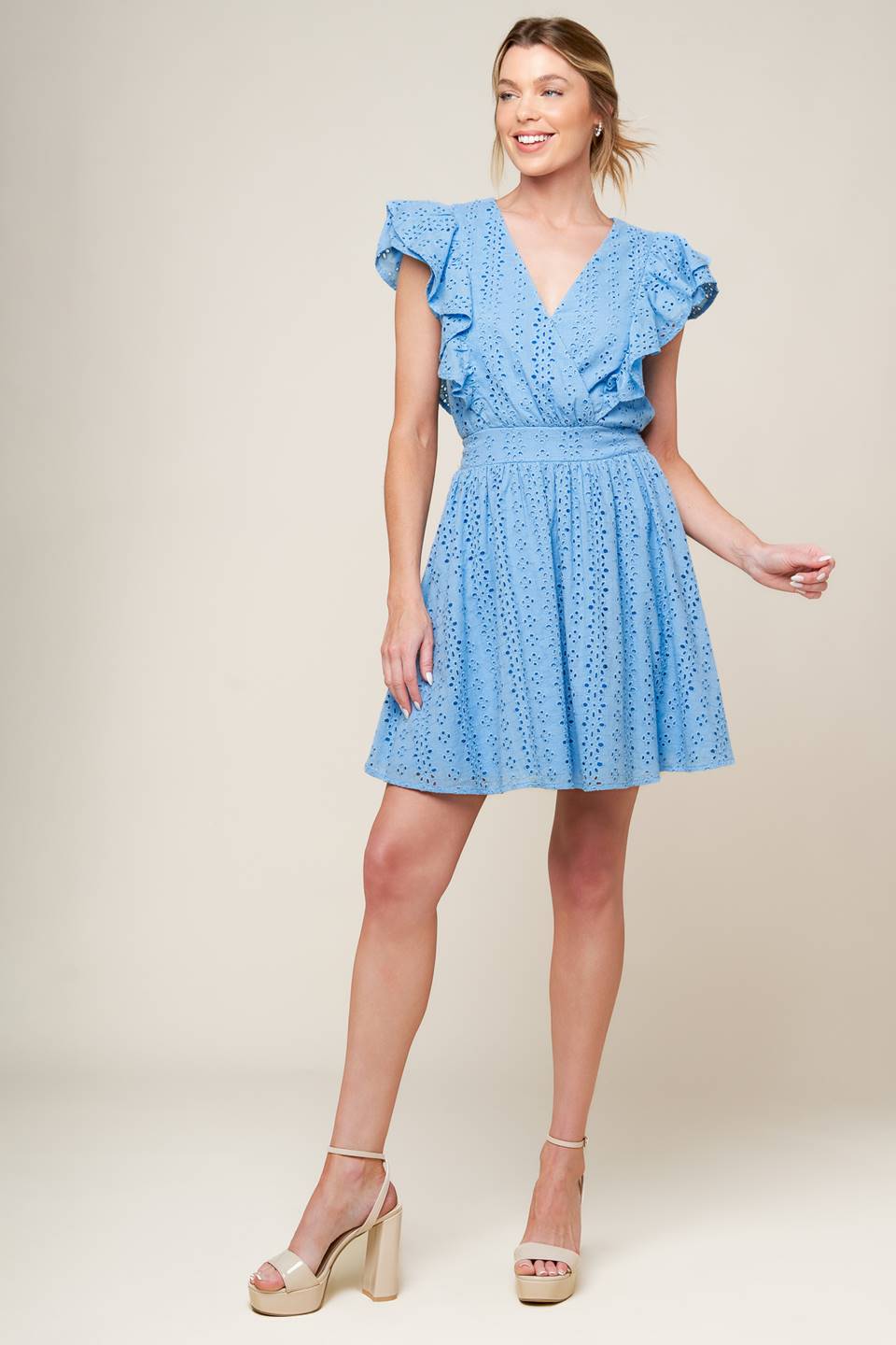 A powder blue woven eyelet mini dress featuring surplice neckline, ruffled sleeve, full skirt and smocked back waistband.