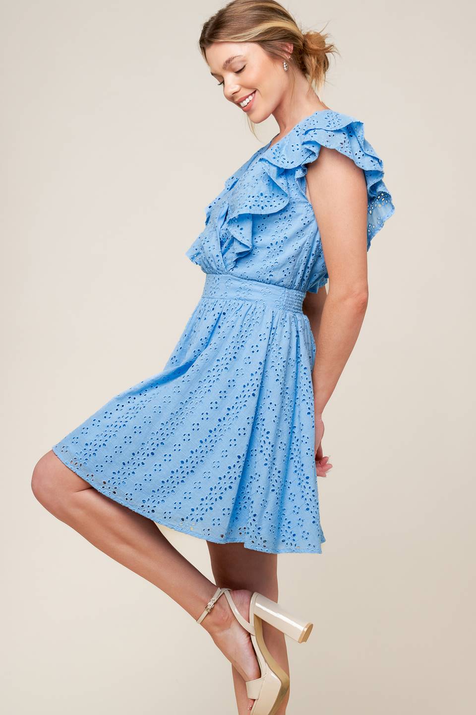 A powder blue woven eyelet mini dress featuring surplice neckline, ruffled sleeve, full skirt and smocked back waistband.