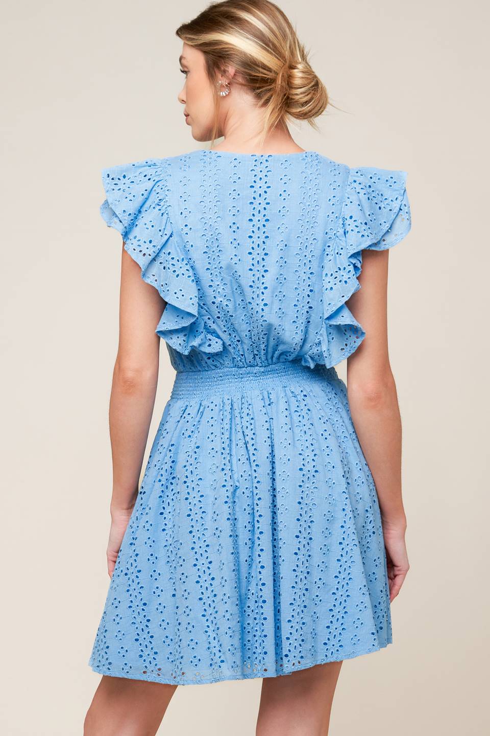 A powder blue woven eyelet mini dress featuring surplice neckline, ruffled sleeve, full skirt and smocked back waistband.