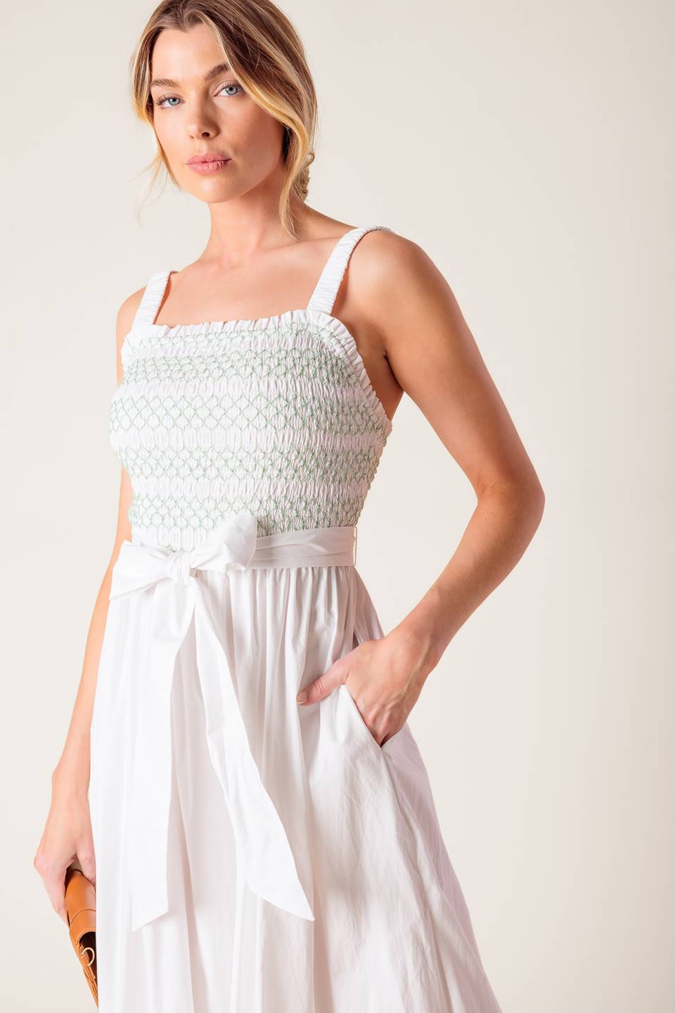 A solid white woven midi dress featuring straight neckline, straps, color smocked bodice and full skirt.