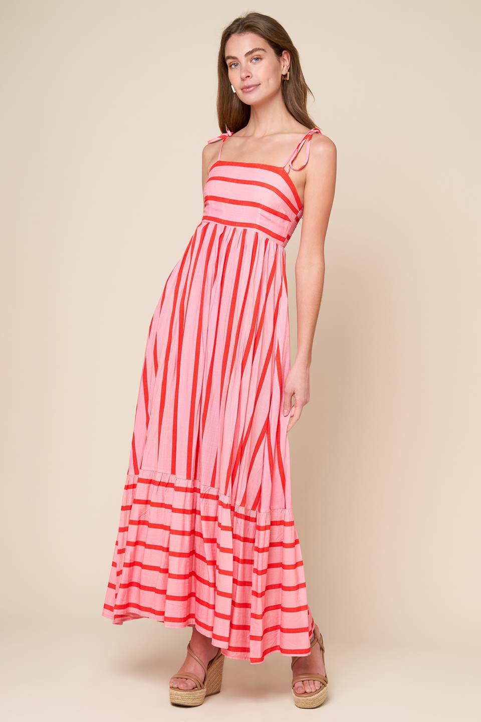 A pink and red striped woven midi dress featuring straight neckline, straps, ruffled hemline and smocked back bodice.