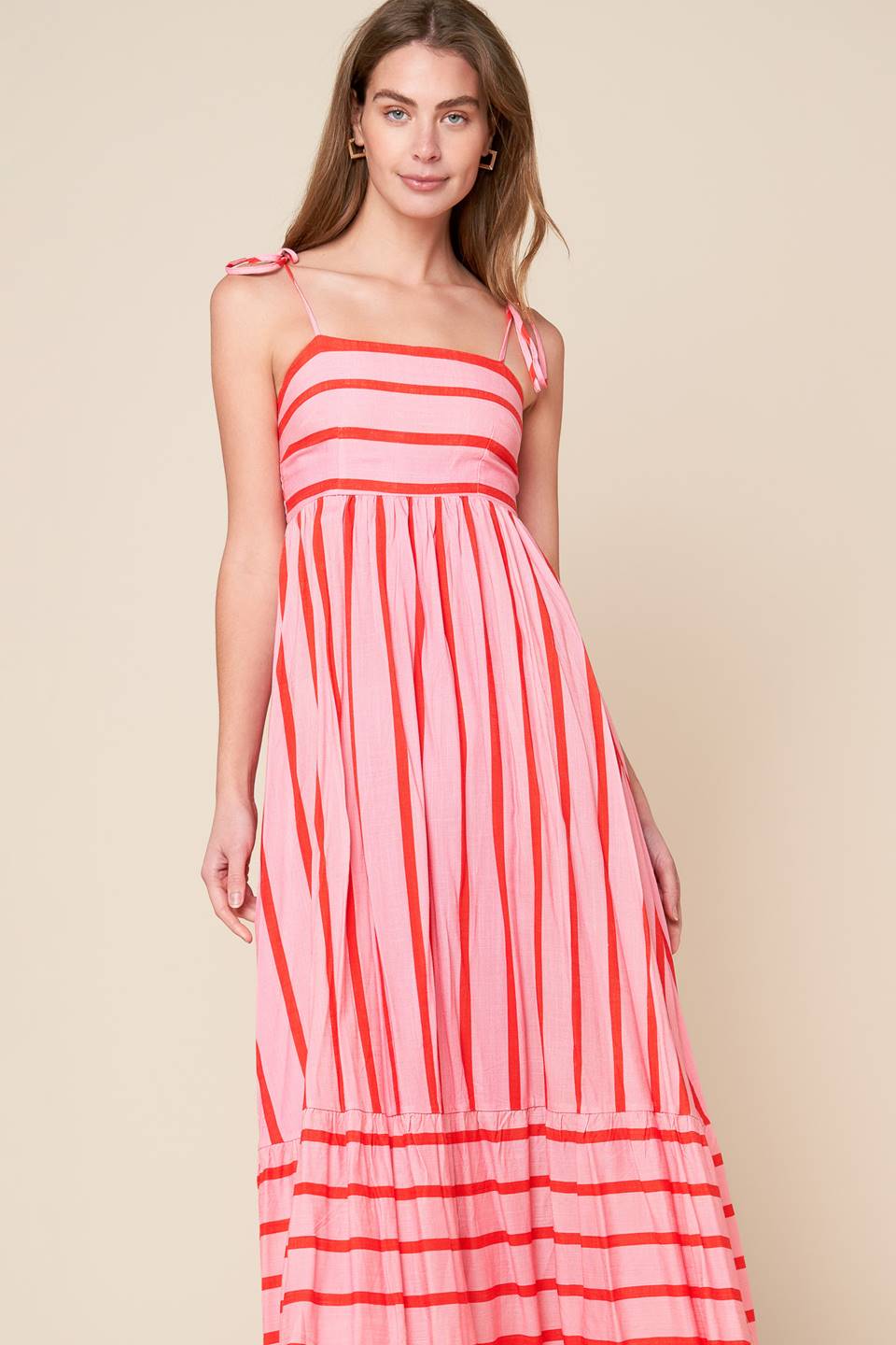 A pink and red striped woven midi dress featuring straight neckline, straps, ruffled hemline and smocked back bodice.