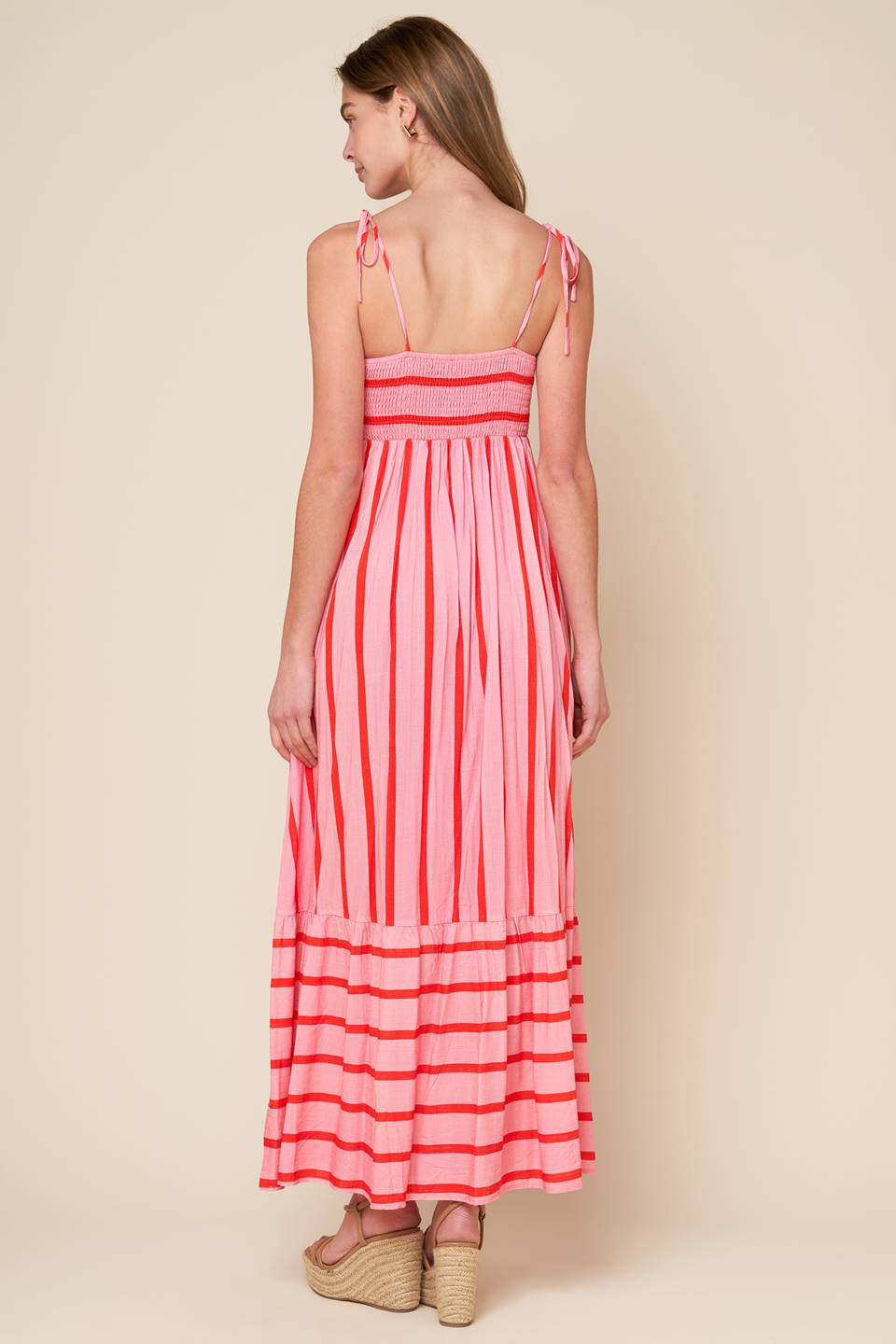 A pink and red striped woven midi dress featuring straight neckline, straps, ruffled hemline and smocked back bodice.