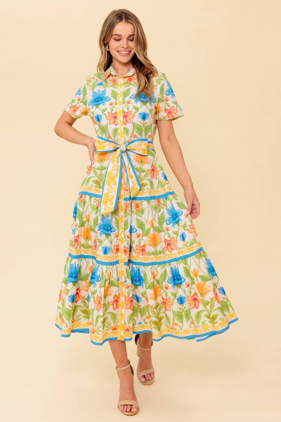 A printed woven midi dress featuring shirt collar, short sleeve, button down, self sash tie and tiered skirt