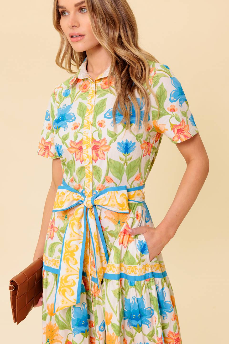 A printed woven midi dress featuring shirt collar, short sleeve, button down, self sash tie and tiered skirt