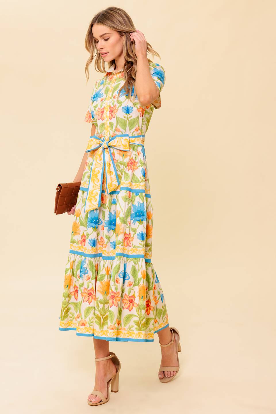 A printed woven midi dress featuring shirt collar, short sleeve, button down, self sash tie and tiered skirt