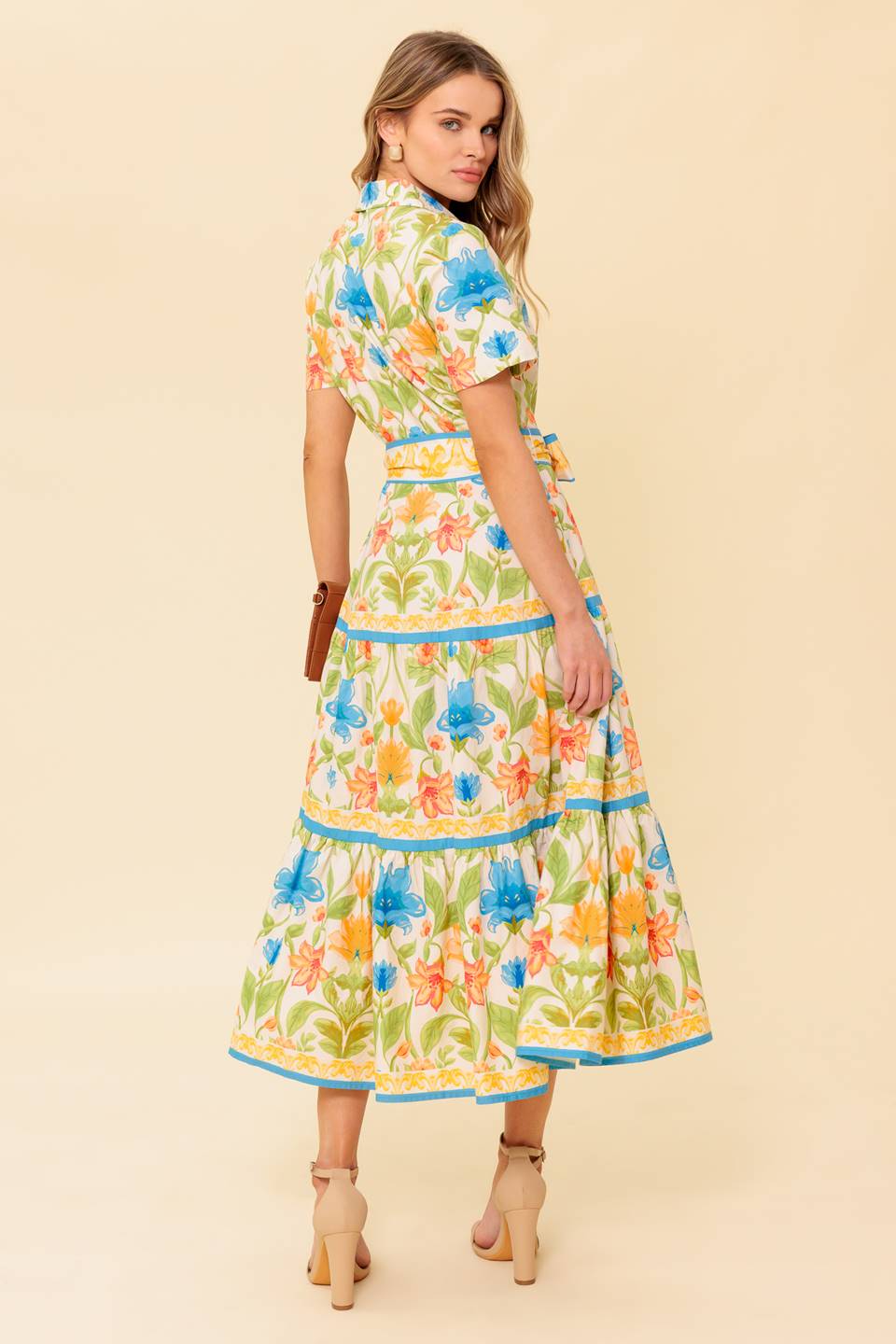 A printed woven midi dress featuring shirt collar, short sleeve, button down, self sash tie and tiered skirt