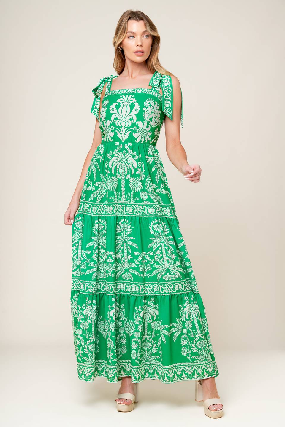 A printed woven maxi dress featuring straight neckline, shoulder ties, tiered skirt and back zipper closure.