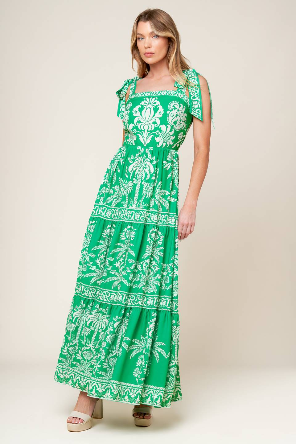 A printed woven maxi dress featuring straight neckline, shoulder ties, tiered skirt and back zipper closure.