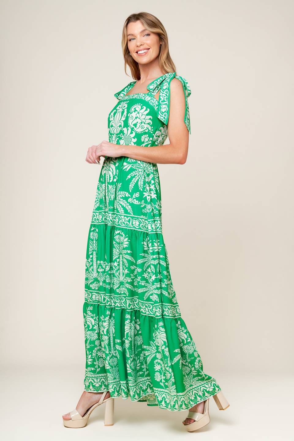 A printed woven maxi dress featuring straight neckline, shoulder ties, tiered skirt and back zipper closure.