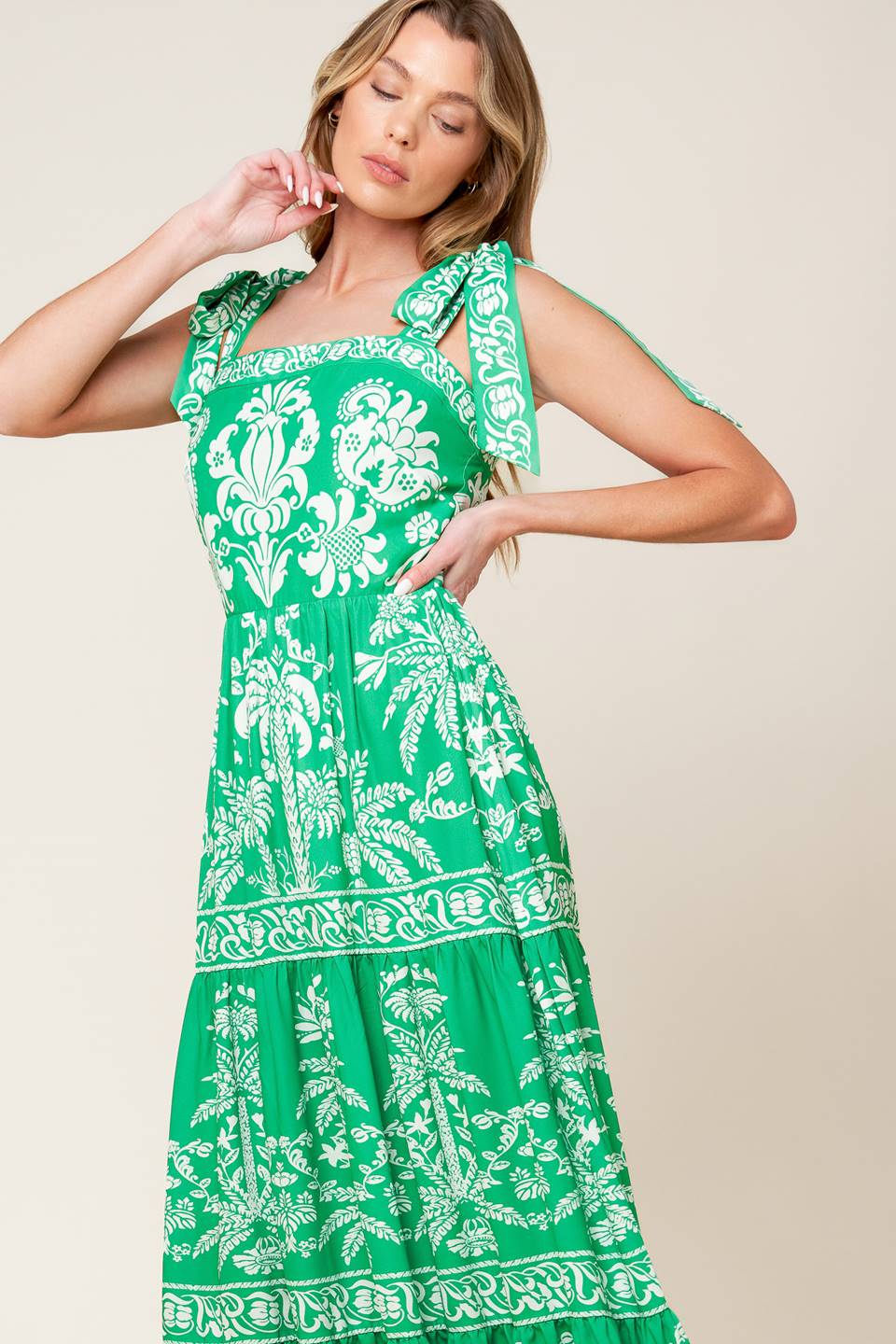 A printed woven maxi dress featuring straight neckline, shoulder ties, tiered skirt and back zipper closure.